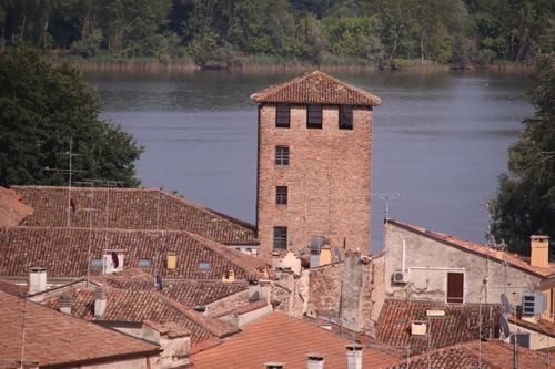 Free View of a historical tower amidst tiled rooftops by a serene river in Mantova, Italy. Stock Photo
