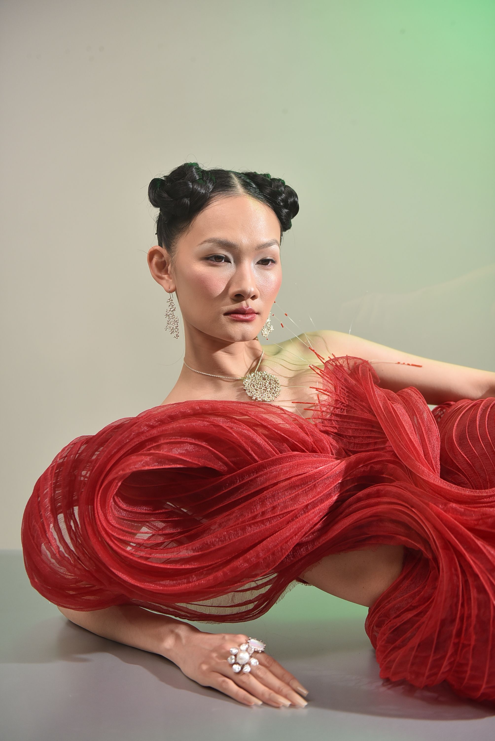 Stunning portrait featuring a model in an elegant red gown with unique hair and jewelry.