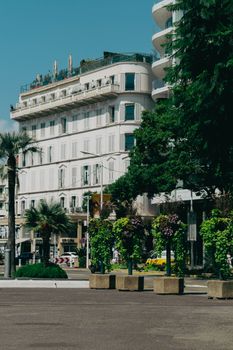 Exterior view of a luxury hotel in Cannes, showcasing iconic architecture amidst tropical greenery.