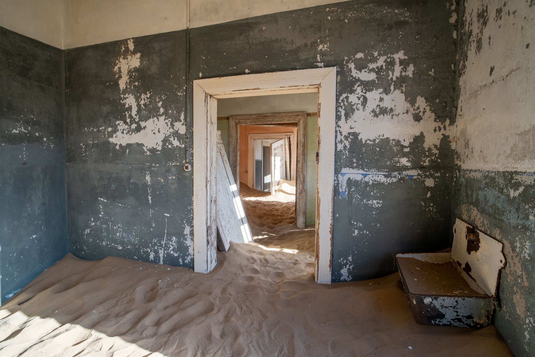 A haunting view of an abandoned room filled with sand in Kolmanskop, a ghost town in the Namib Desert, Namibia.