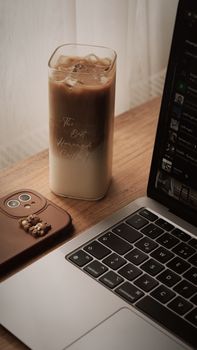 A cozy workspace featuring a refreshing iced coffee and a sleek laptop. - Fotografer Sidoarjo