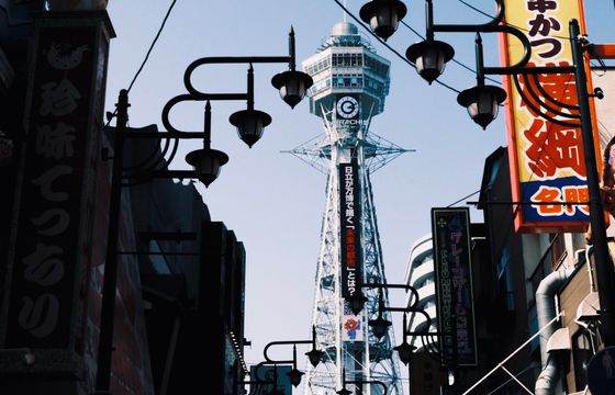 Japan eSIM offer: Tsutenkaku Tower in Osaka's vibrant Shinsekai district framed by traditional street lamps.