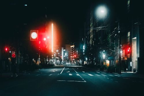 Free A quiet, illuminated city street scene at night with glowing traffic lights and empty roads. Stock Photo