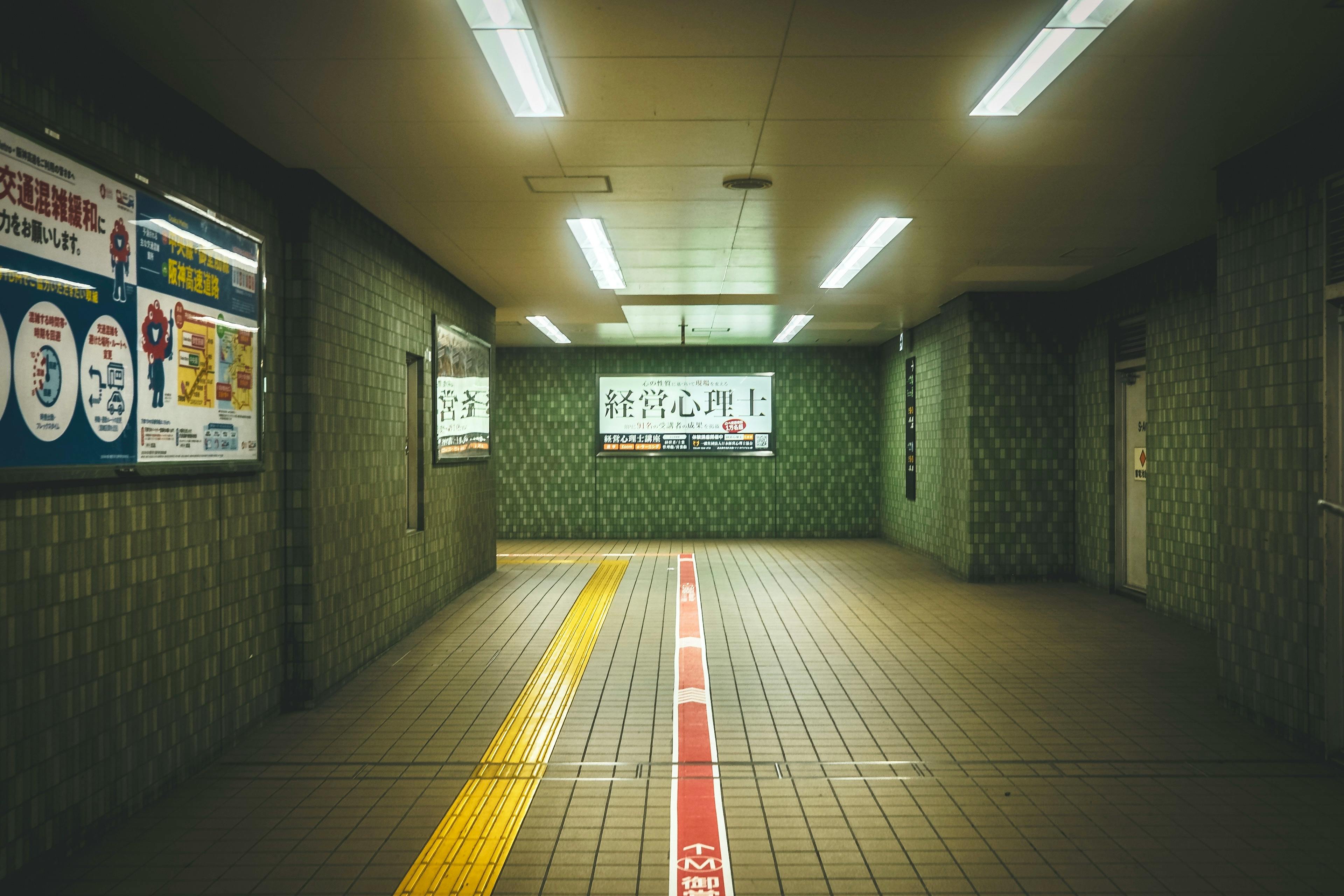 A deserted subway hallway with illuminated signs and tiled walls in a city setting.