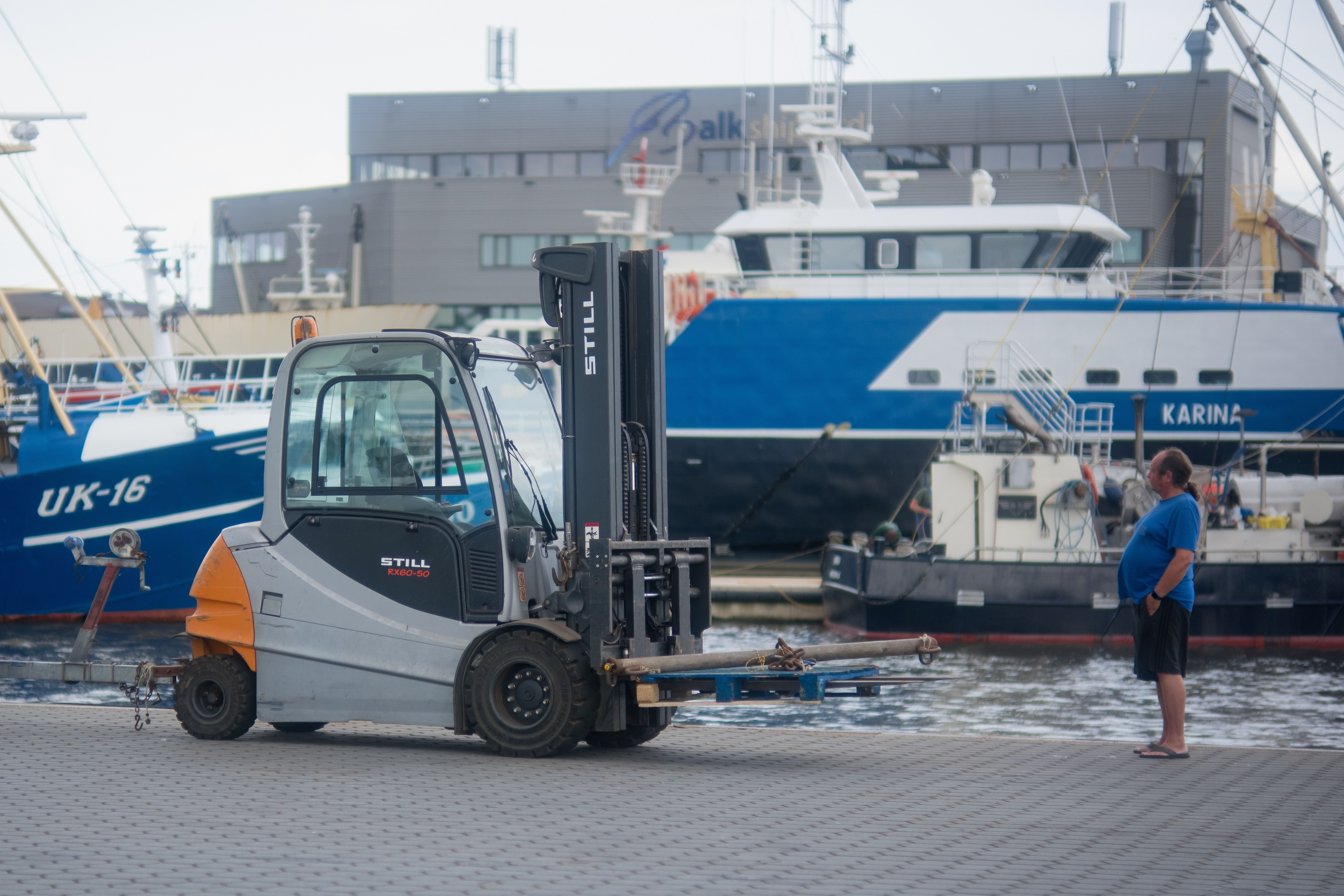 Forklift operating in Urk harbor, Flevoland with ships in the background, urban scenery.