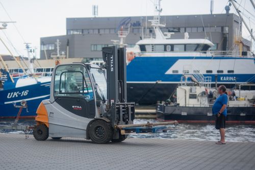 Free Forklift operating in Urk harbor, Flevoland with ships in the background, urban scenery. Stock Photo