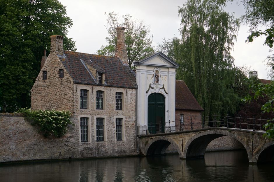 Tourists cycling alongside a picturesque canal in Bruges, Flanders.