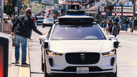 A self-driving car navigates through a bustling city street in San Francisco, capturing urban mobility in action.