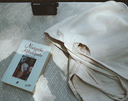 A copy of 'Nietzsche Ağladığında' by Irvin D. Yalom on a patterned surface beside a tote bag.