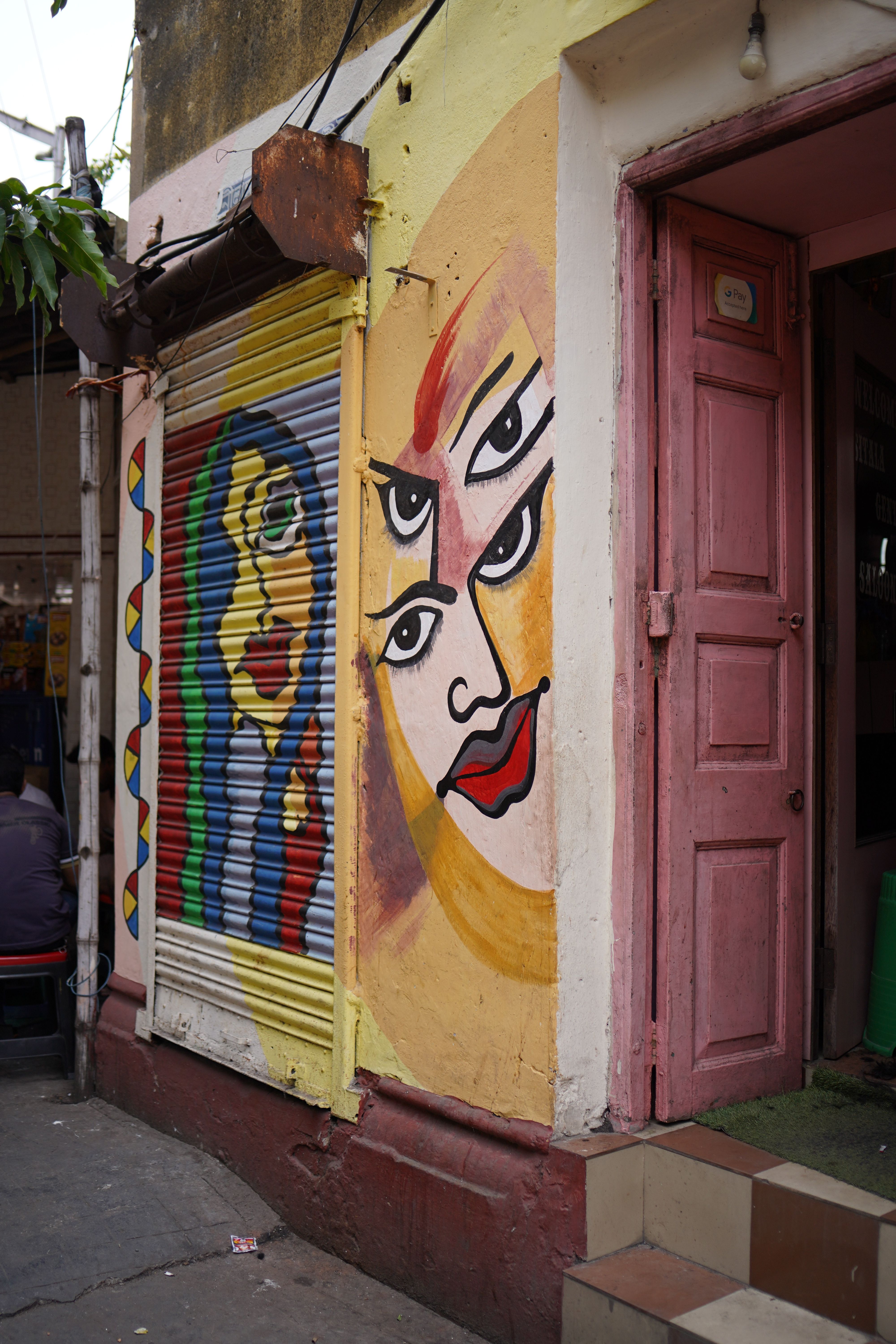 Colorful street art featuring abstract faces on a Kolkata street.