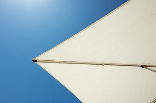 Free A minimalist shot of a beach umbrella contrasting against a clear blue sky, evoking a sense of summer relaxation. Stock Photo