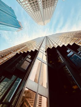 Dramatic view of city skyscrapers ascending into clear blue sky, showcasing modern architecture.