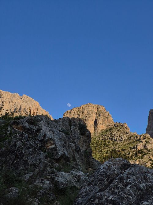 Free Stunning view of rugged mountains under a clear evening sky with the moon visible. Stock Photo
