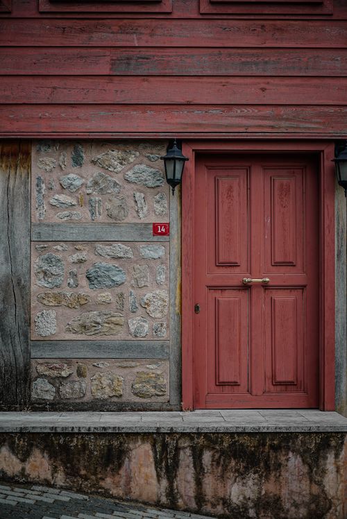 Free A rustic red wooden door on a stone building facade, showcasing vintage architecture. Stock Photo