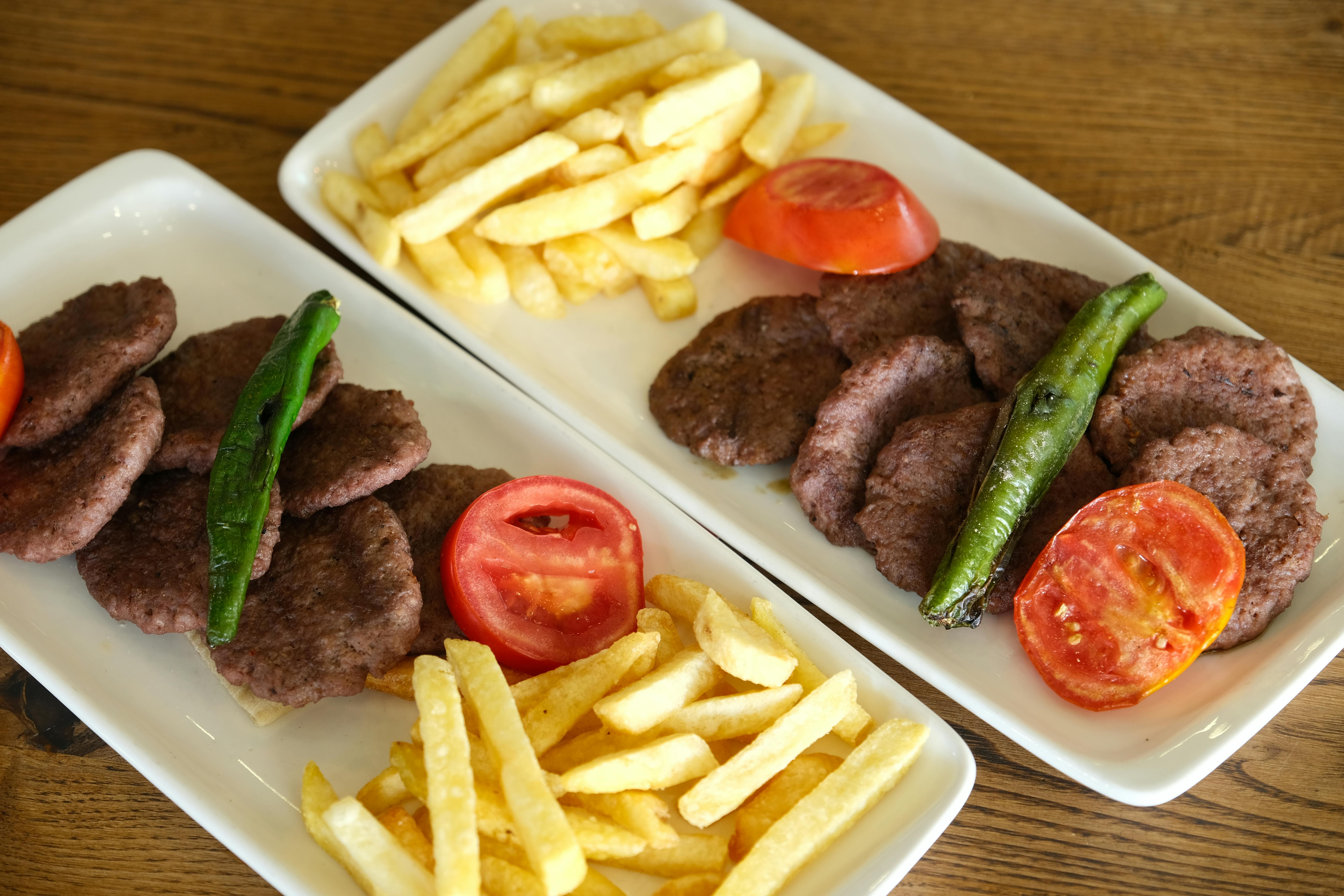 Free Traditional Turkish meatballs with fries, peppers, and tomatoes on a wooden table. Stock Photo