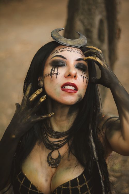 Free A woman with celestial face paint and crescent moon accessory, set in a forest. Stock Photo