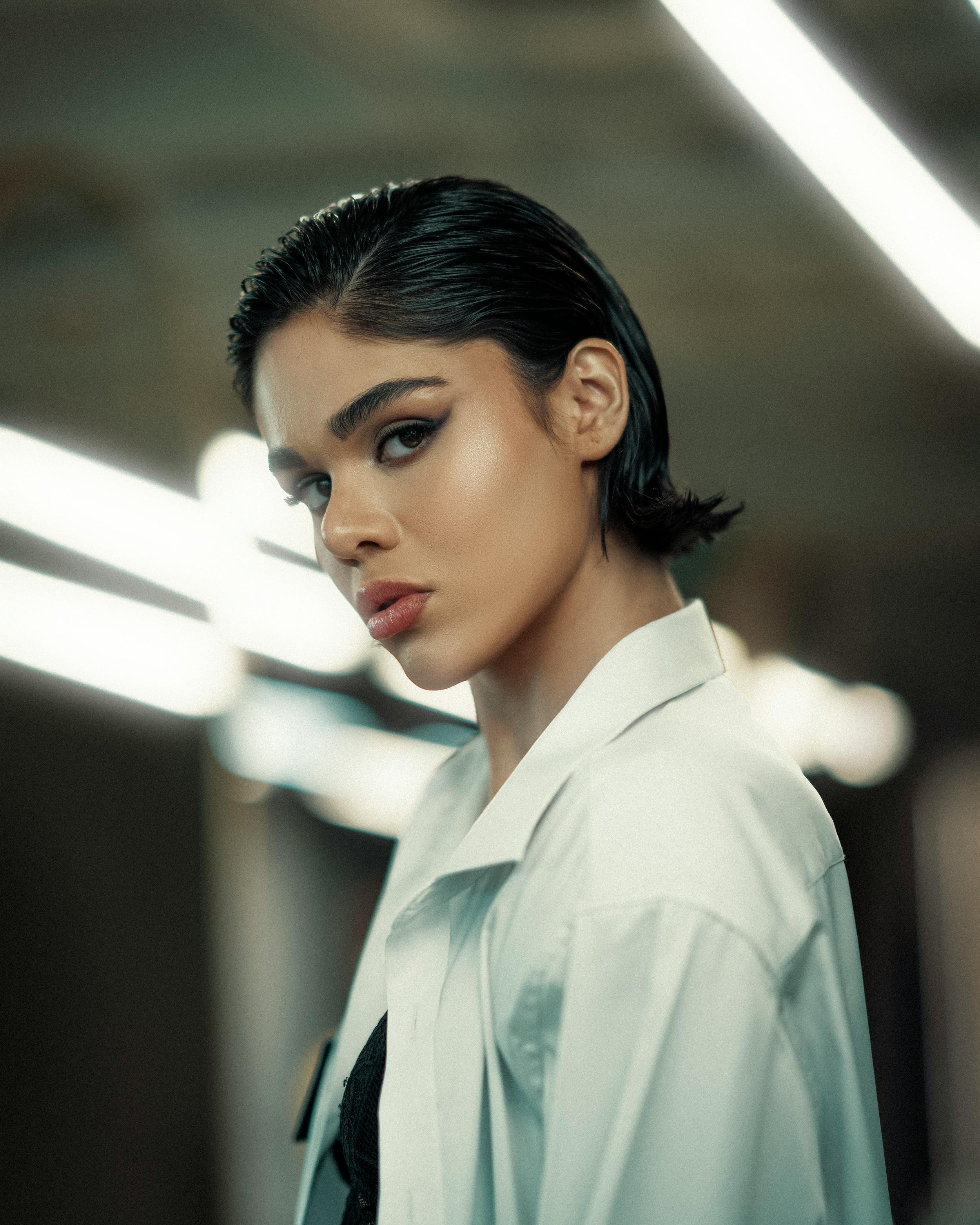 Elegant portrait of a woman with bold makeup and slicked-back hair, exuding modern style and confidence.