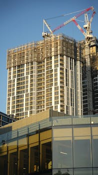 Towering skyscraper under construction with prominent crane against clear sky.