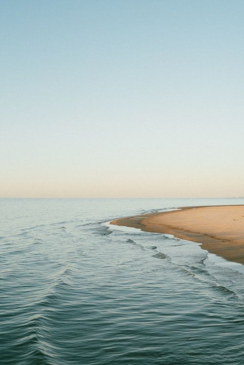 Free A tranquil beach scene at sunrise with gentle waves lapping the sandy shore. Stock Photo