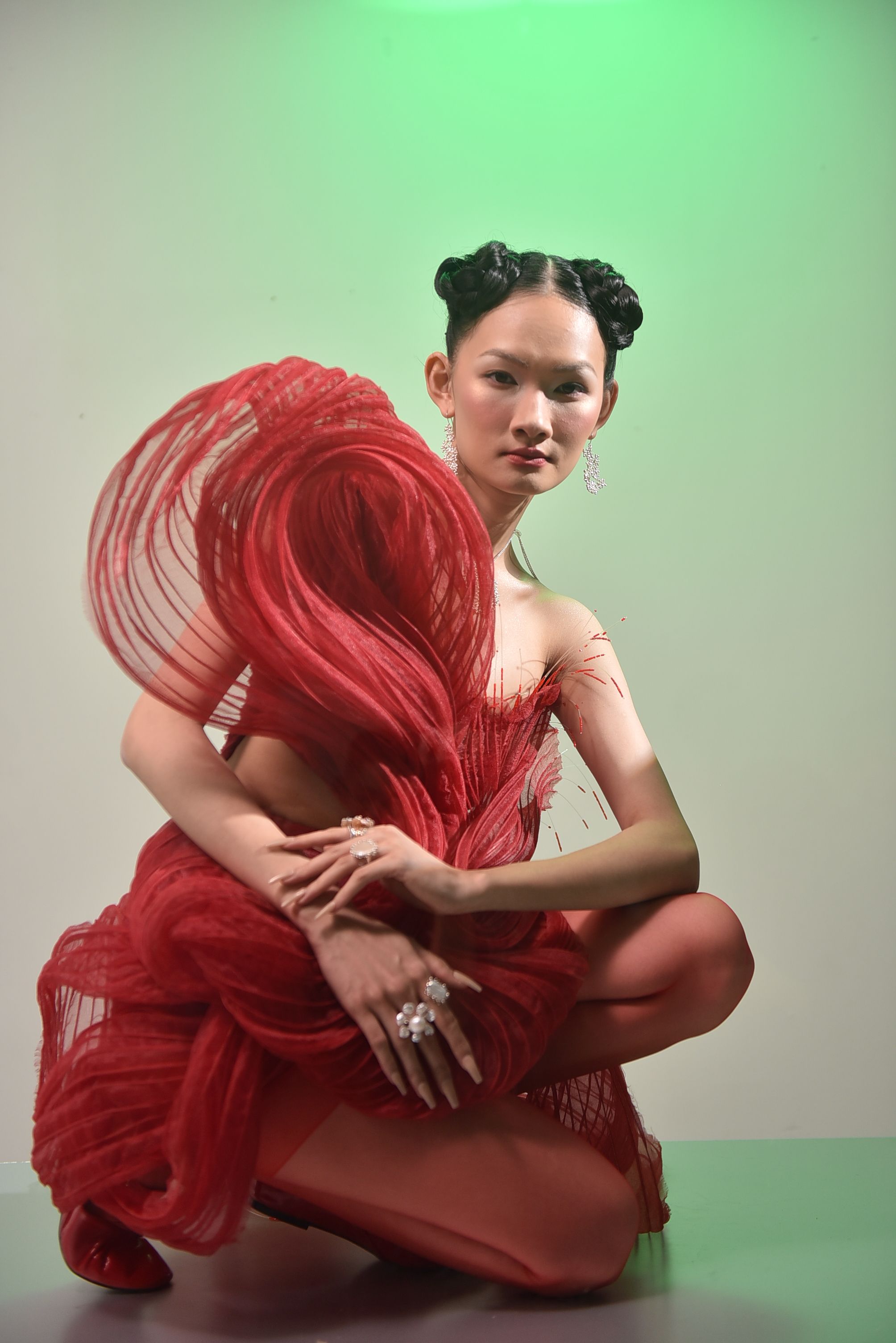 Artistic portrait of a woman in a striking red dress with unique hair and lighting.