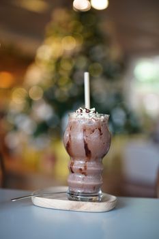 Indulge in a rich chocolate milkshake topped with whipped cream in a warm cafe setting.