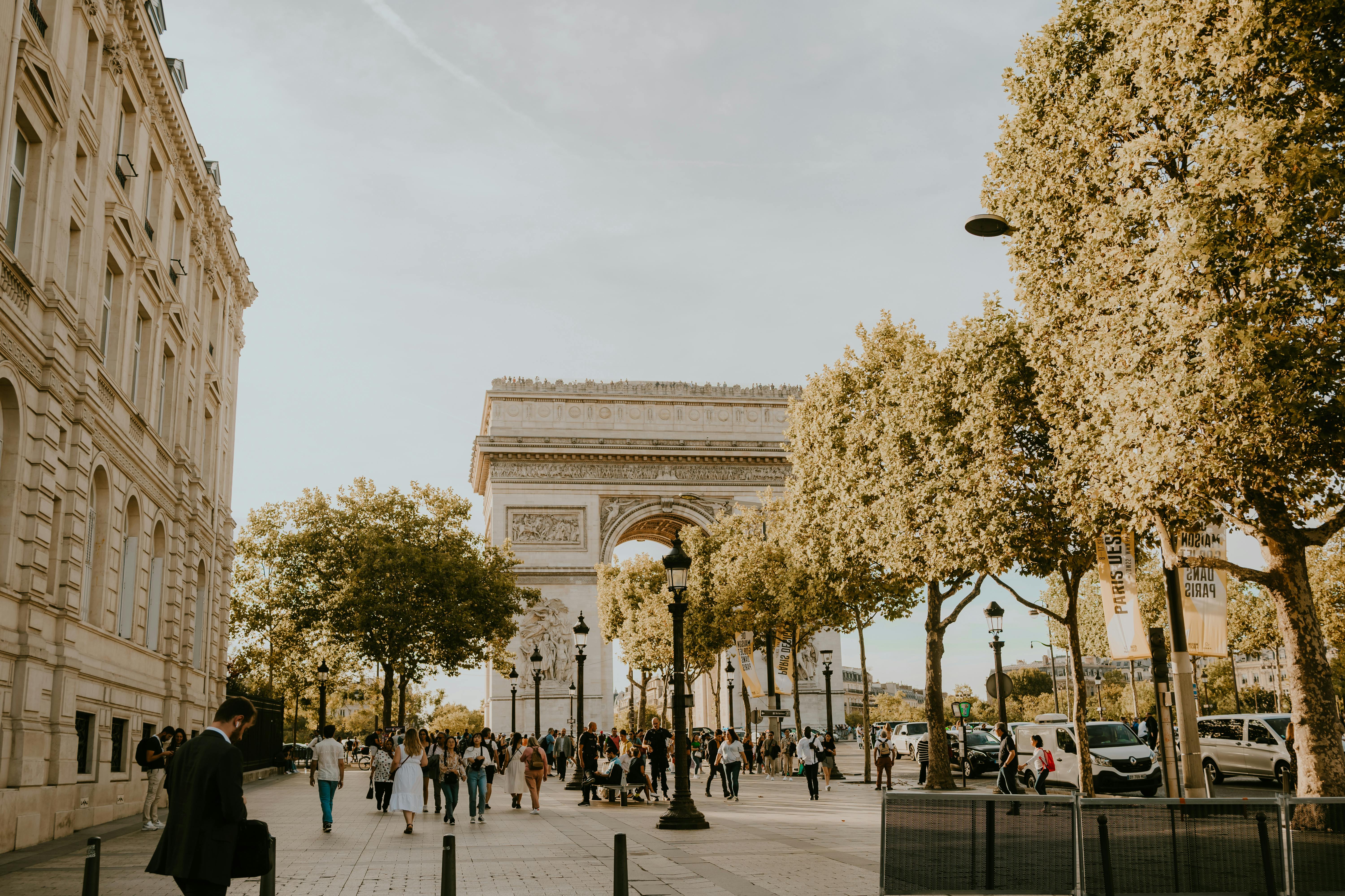 Charming view of the iconic Arc de Triomphe surrounded by people enjoying a lovely evening in Paris.