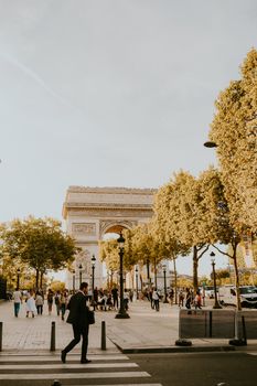 Stunning view of the Arc de Triomphe with people strolling around on a bright day in Paris.