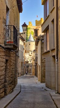 Explore a picturesque medieval street in Olite, Spain, featuring historic architecture and a castle view.