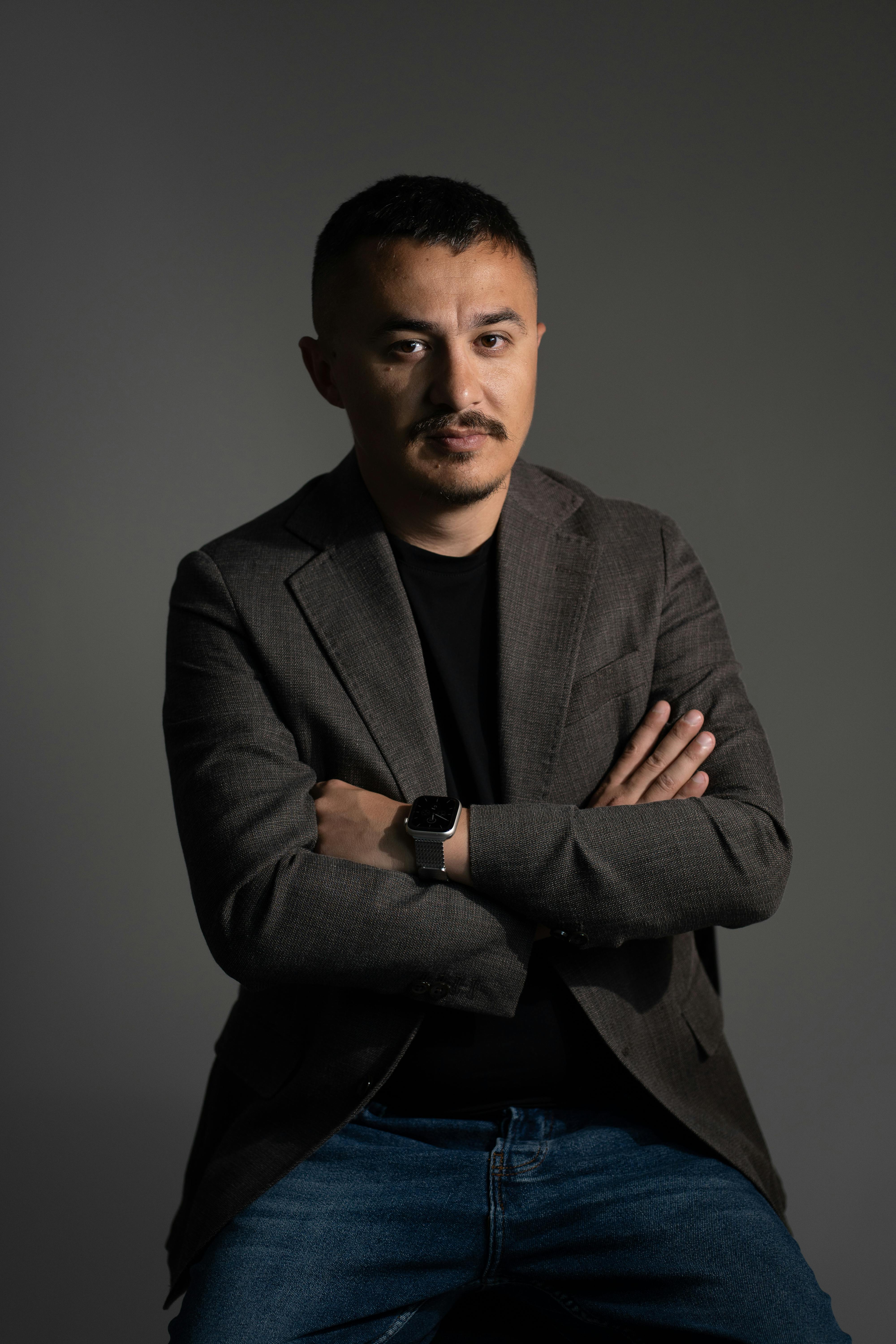 Free A confident man in business casual attire poses in a studio environment, arms crossed. Stock Photo