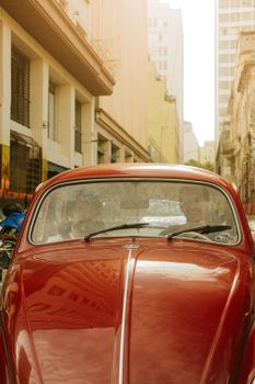 Classic red car parked on a bustling São Paulo street, capturing urban life.