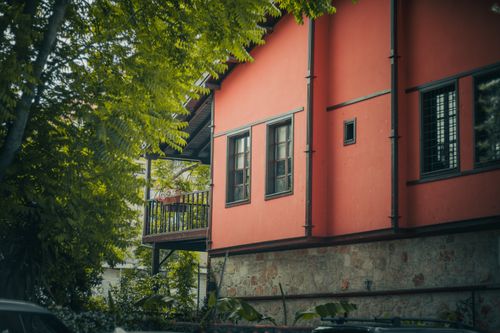Free A traditional red house surrounded by lush foliage, evoking a feeling of tranquility and nature. Stock Photo