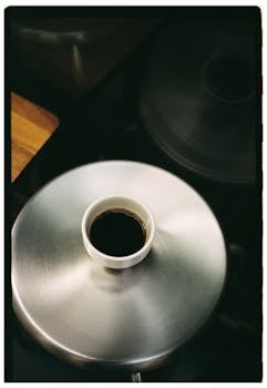 Overhead shot of a cup of coffee on a stainless steel surface, creating a minimalist aesthetic.