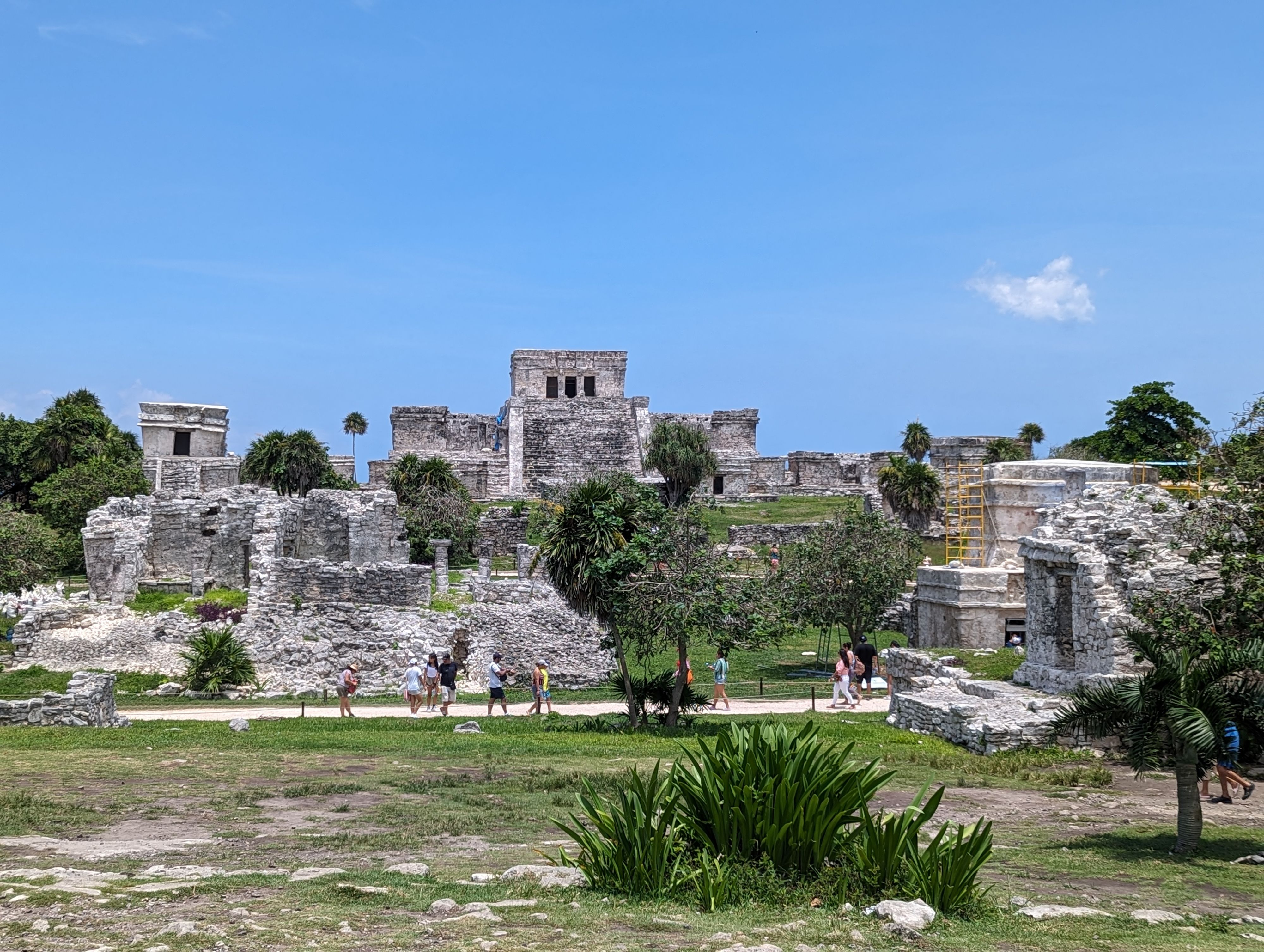 Visitors exploring ancient Mayan ruins under a clear blue sky in Mexico