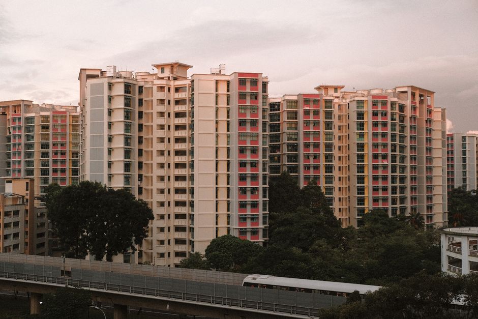 Vue au coucher du soleil sur des immeubles colorés entourés de verdure, reflet de la vie urbaine.