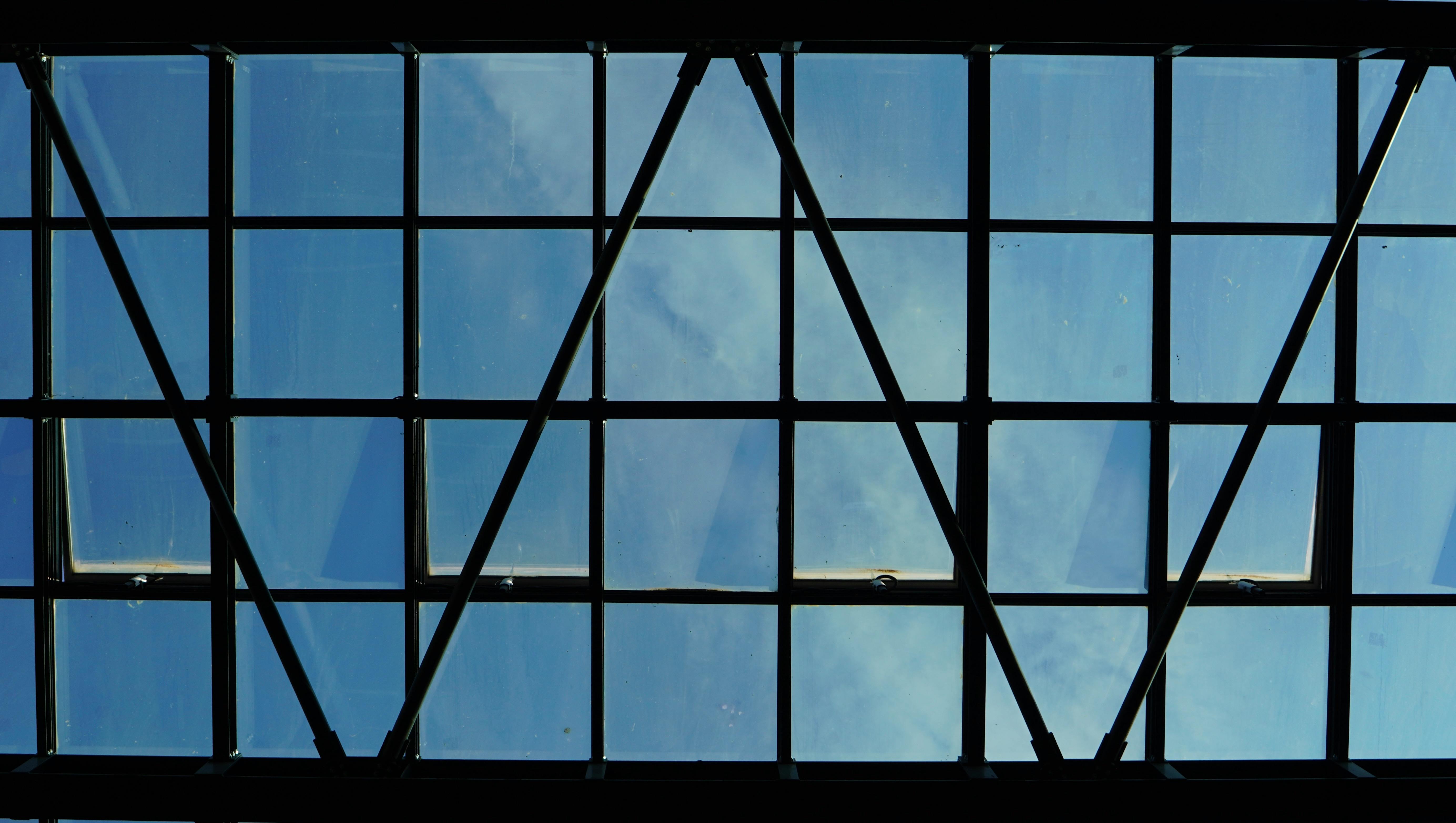 gratis Glazen plafond met uitzicht op de blauwe lucht, een toonbeeld van modern architectonisch ontwerp. Stockfoto