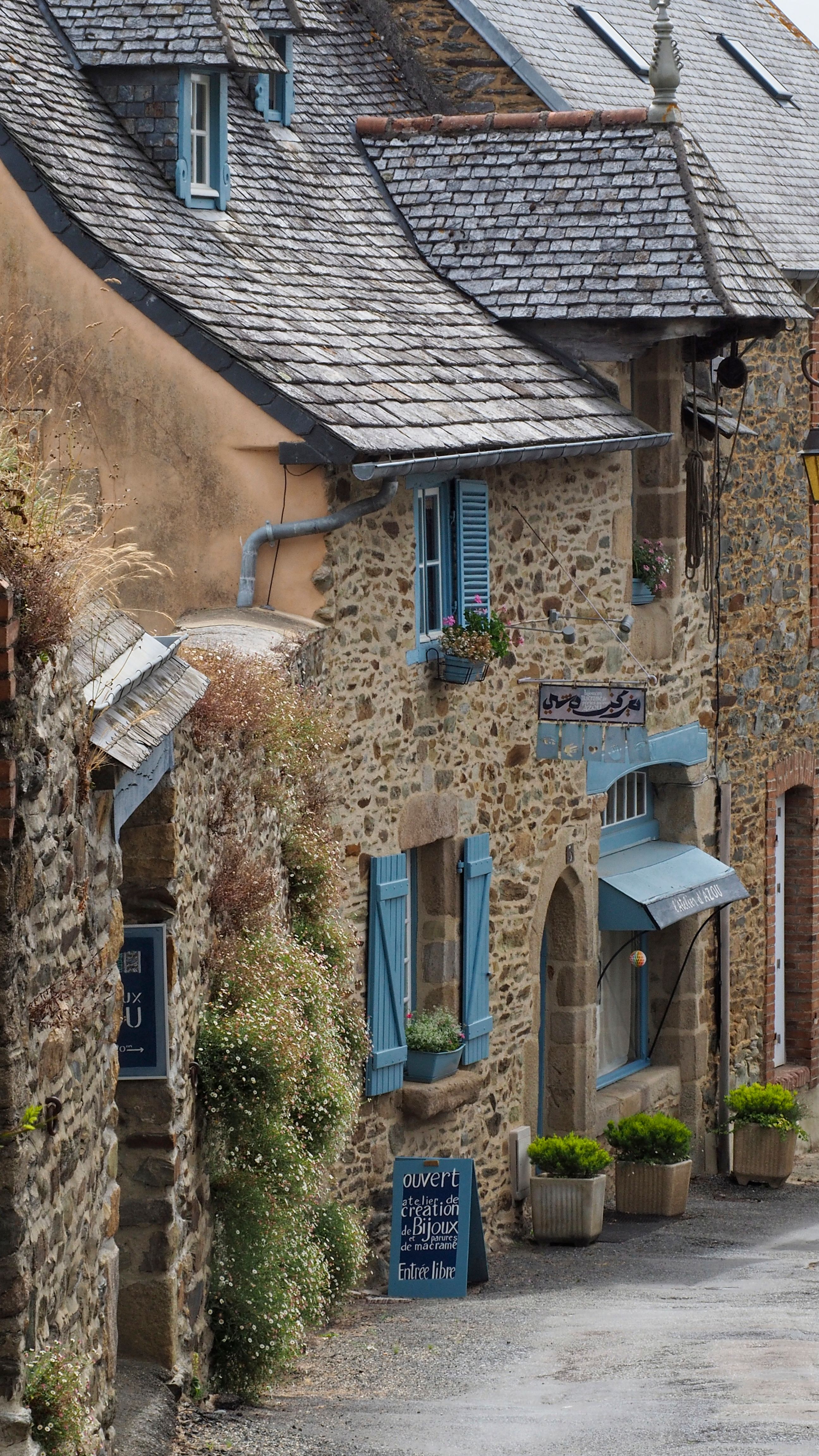 Picturesque street with stone houses in Tréguier, Bretagne, showcasing blue shutters and rustic charm.
