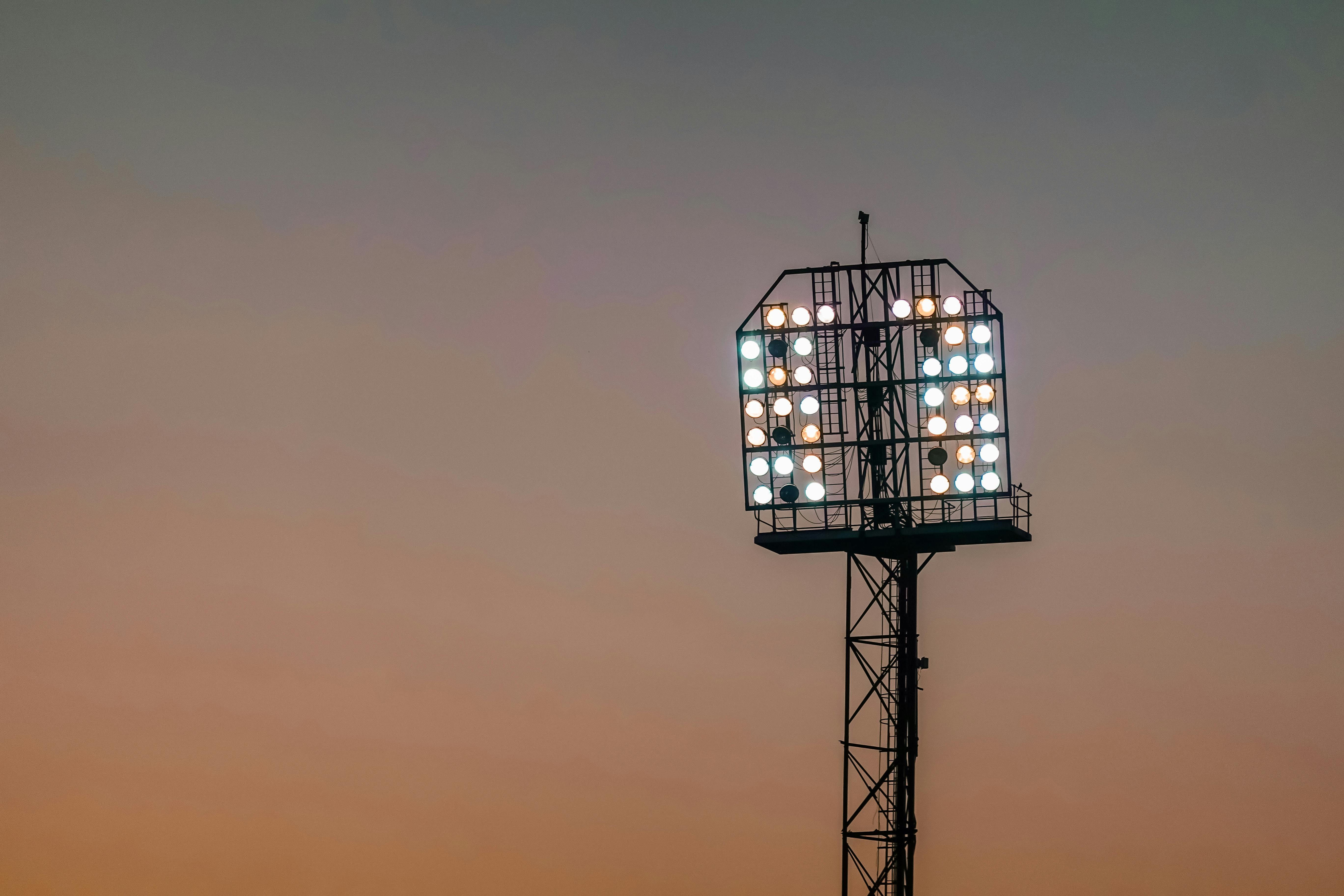 A detailed view of stadium floodlights set against a colorful sunset sky, highlighting sports venue ambience.