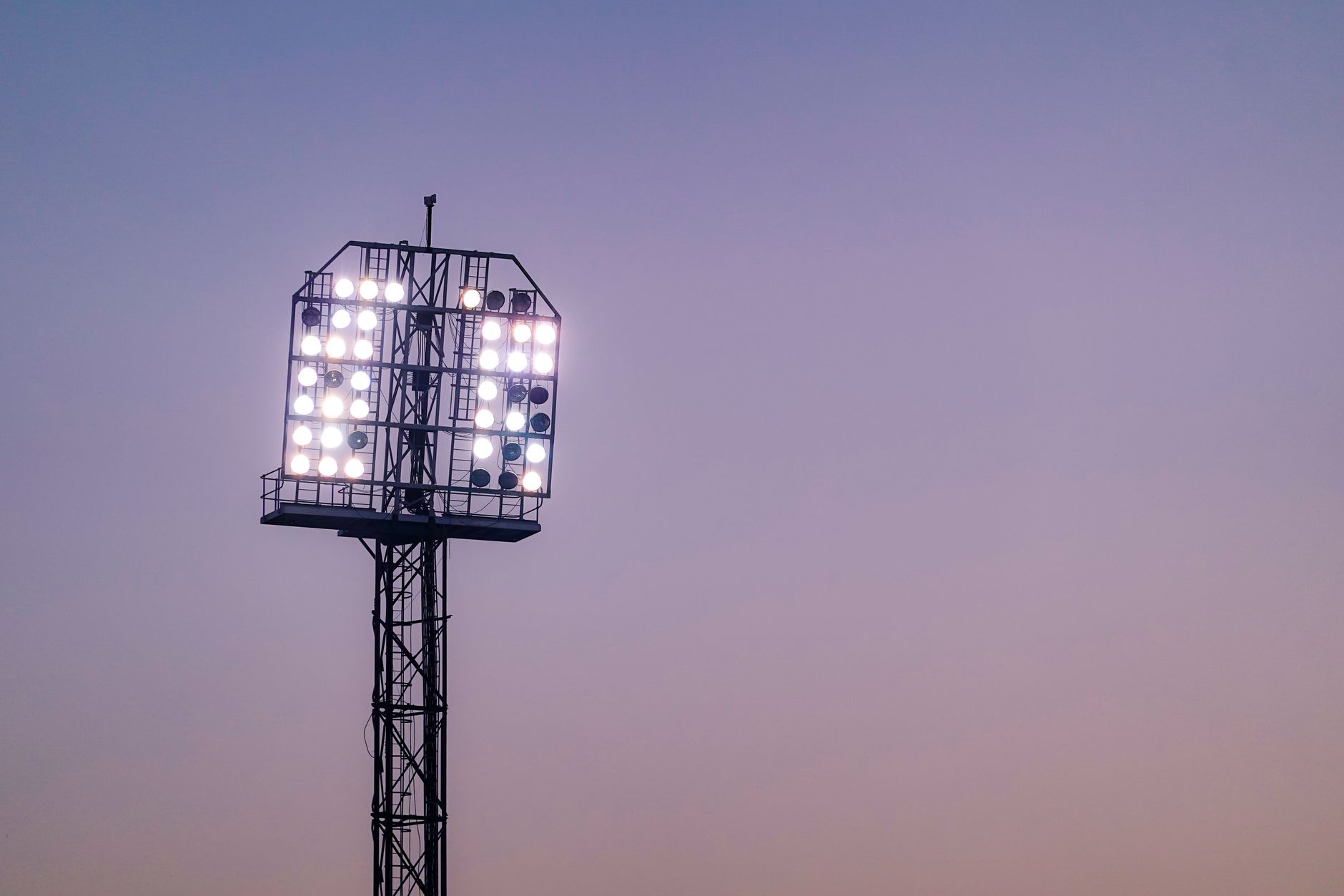 Bright stadium floodlights illuminating the sky during twilight.