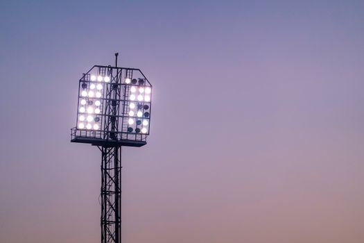 Bright stadium floodlights illuminating the sky during twilight.