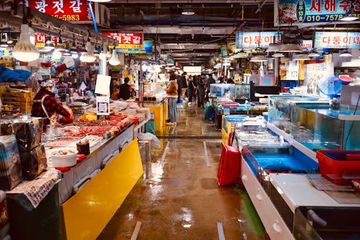 Bustling indoor market with various seafood stalls and shoppers.