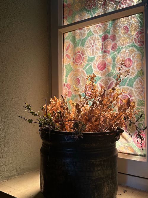 Free Dried flowers in a vintage pot with glowing stained glass backdrop. Warm tones. Stock Photo