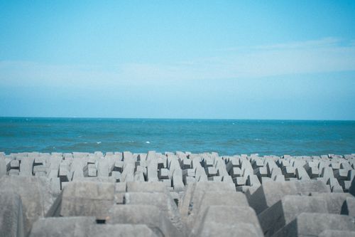 Free A scenic view of a coastal breakwater structure against a vast blue sea and sky, exuding tranquility. Stock Photo