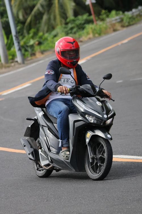 Free Person in a red helmet riding a motorcycle on an urban street during the day. Stock Photo