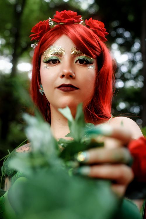Free Portrait of a woman in a vibrant floral crown and makeup in a lush forest setting. Stock Photo