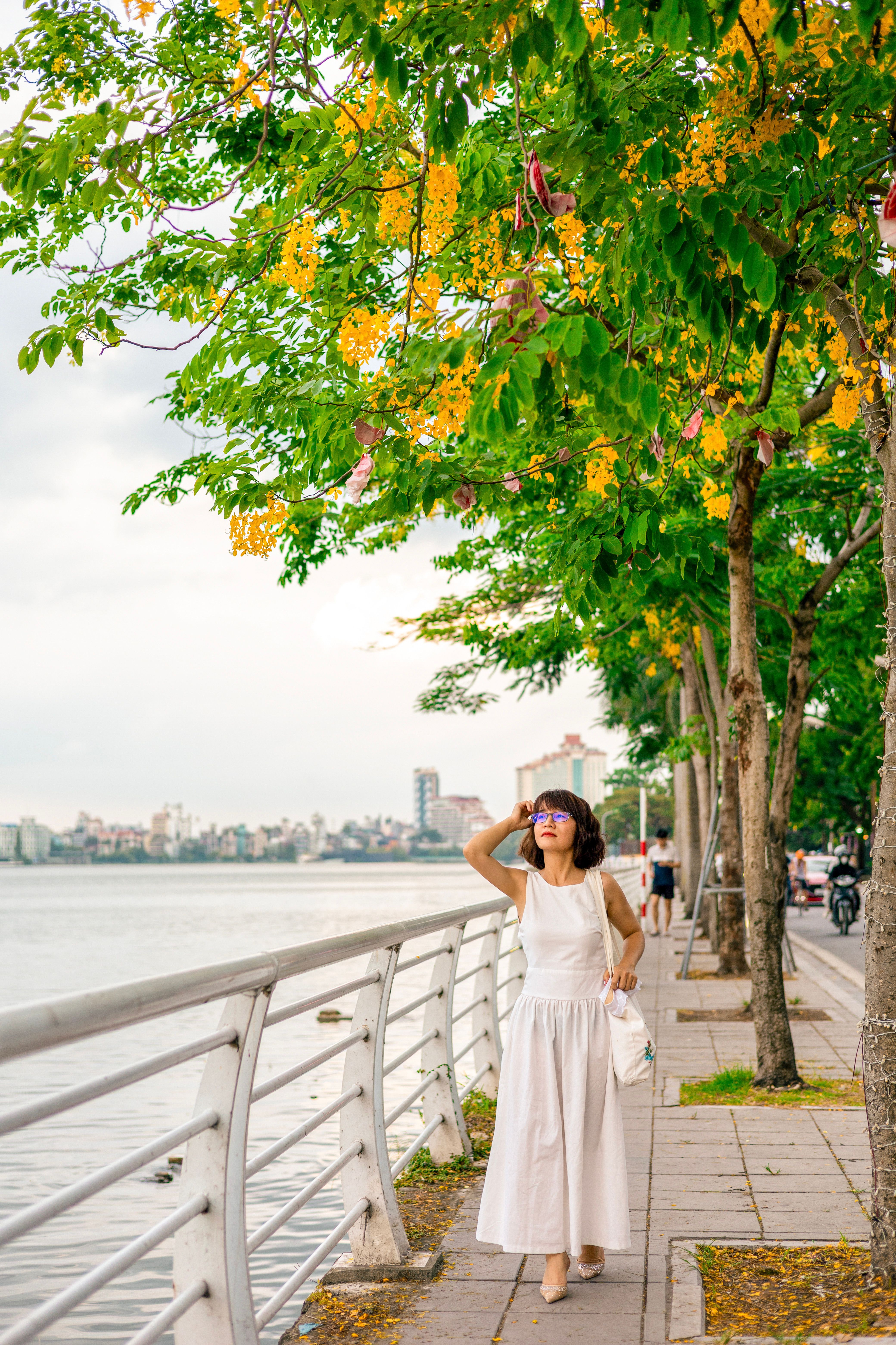 Woman Strolling on Riverside Pathway in Summer · Free Stock Photo