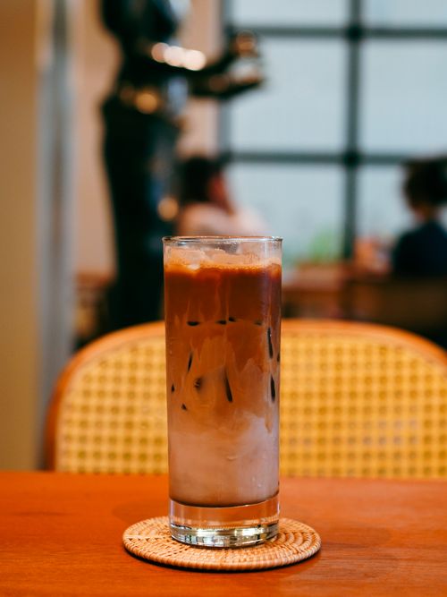 Free Tall glass of iced coffee on table in a warm cafe ambiance. Stock Photo