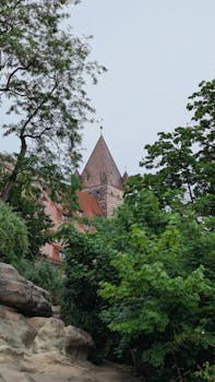 A picturesque view of the Nuremberg Castle tower amidst lush greenery, under an overcast sky.