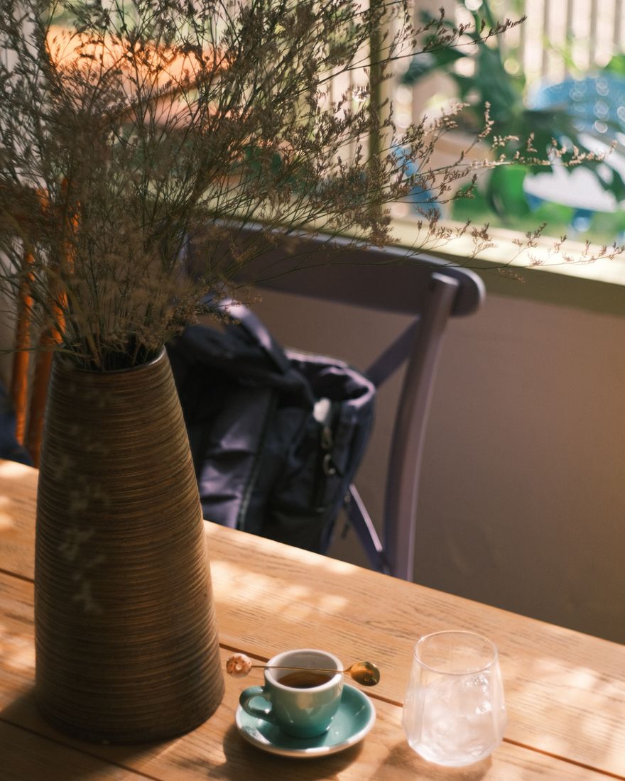 Coffee, a glass of water and a small vase in afternoon light