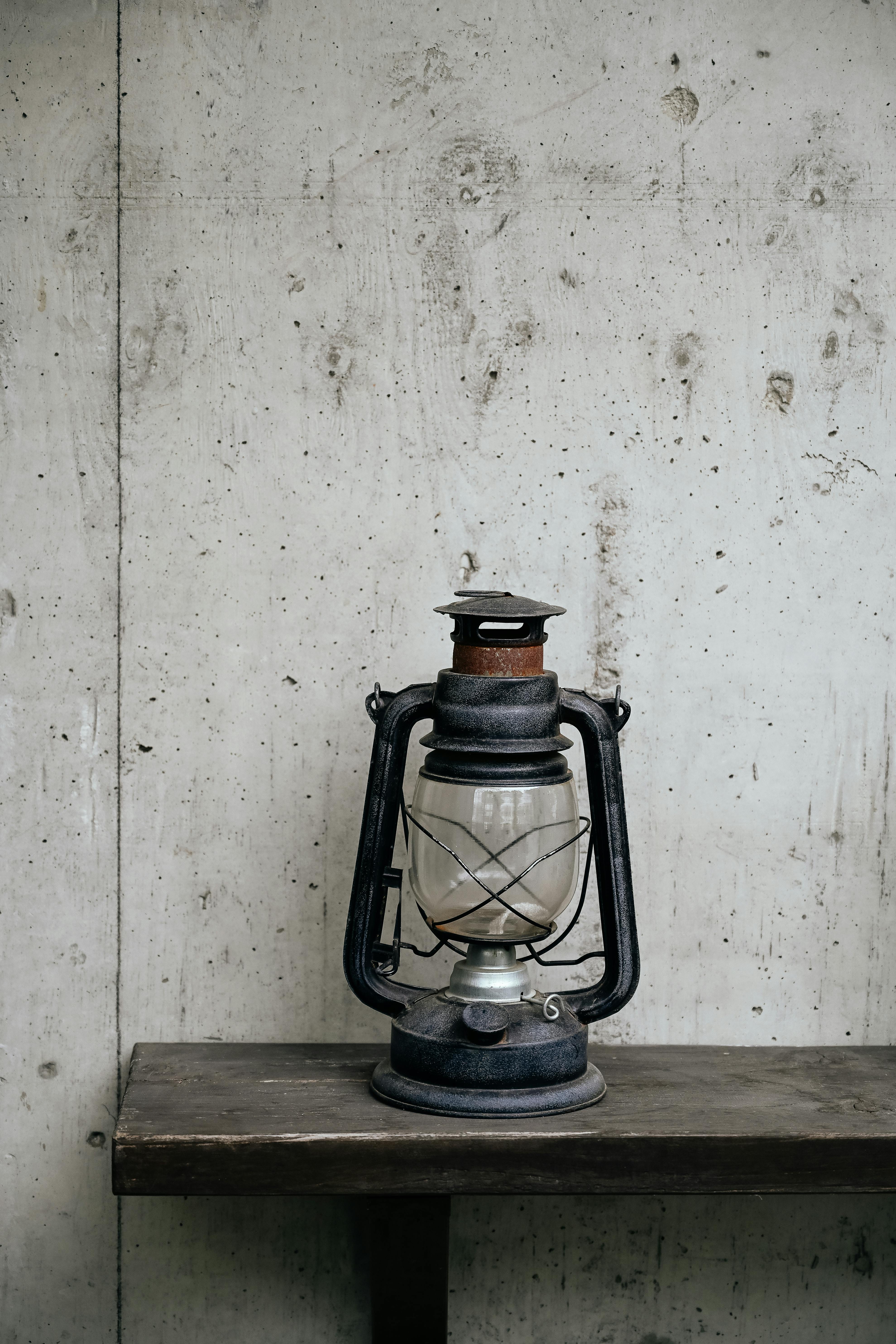 A classic oil lamp resting on a wooden shelf against a concrete wall in Nanjing, China.
