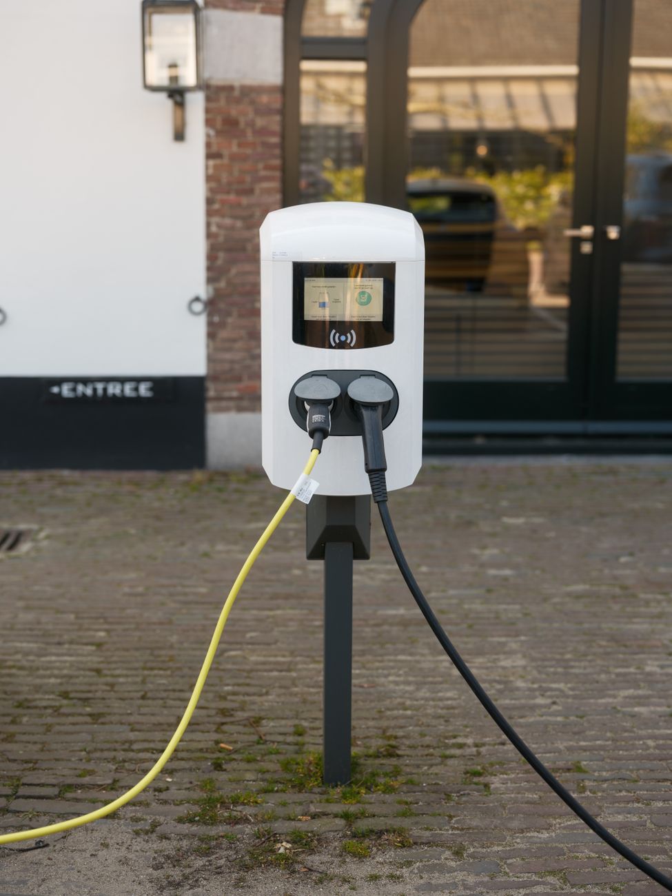 Buitenlaadstation voor elektrische voertuigen met aangesloten kabels.